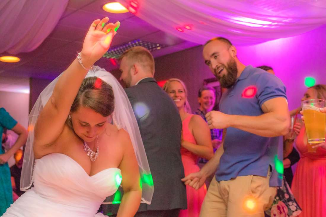Guests dancing beneath colorful reception lighting